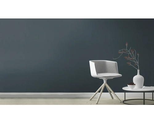 Wohnzimmer mit Stuhl, Tisch und Dekoration vor einer dunklen Wand.