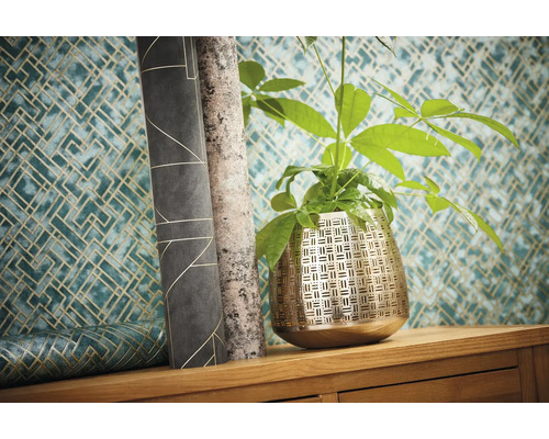 Szene mit Zimmerpflanze in einem Metalltopf und Tapetenrollen mit geometrischen Mustern