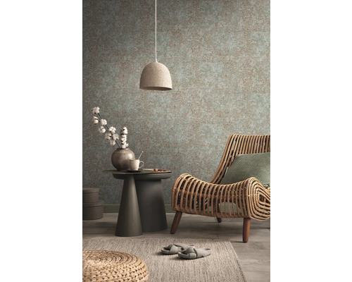 Gemütliches Interieur mit Rattansessel, Beistelltisch, Lampe und gemusterter Tapete