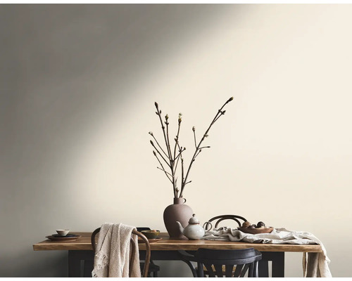 Esszimmer mit Holztisch, Geschirr und Zweigen in einer Vase vor einer gestrichenen Wand