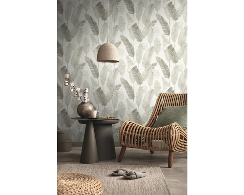 Wohnzimmer mit Blättertapete, Rattan-Sessel und Beistelltisch
