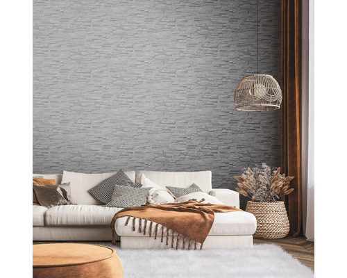 Wohnzimmer mit Sofa, Dekokissen und Wandtapete in Steinoptik.