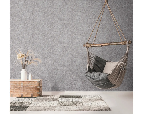 Hängesessel mit Kissen, Holztruhe mit Dekoration und Teppich in einem hellen Raum.