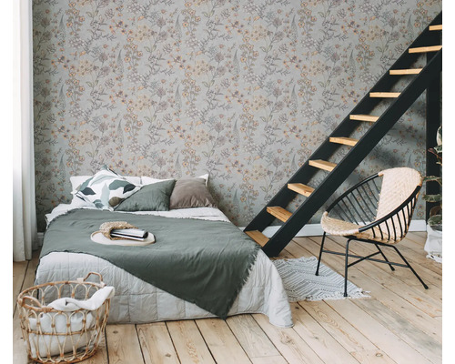 Schlafzimmer mit floral gemusterter Tapete, Bett, Leiter und Korbsessel