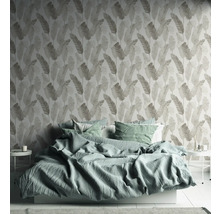 Schlafzimmer mit Bett und gemusterter Tapete mit Blattmotiv