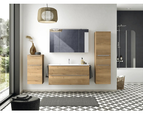 Badezimmer mit Waschtisch, Spiegelschrank, Hochschrank, Badewanne und gemusterten Fliesen.