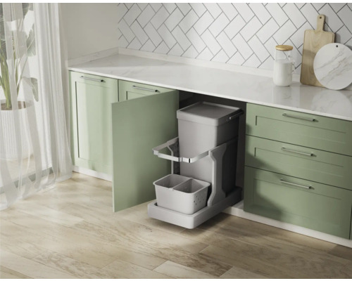 Küchenszene mit einem ausziehbaren Mülleimer in einem grünen Küchenschrank