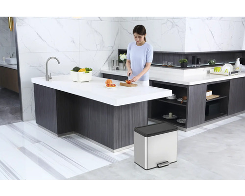 Küchenszene mit Kücheninsel, Mülleimer und einer Person, die Obst schneidet