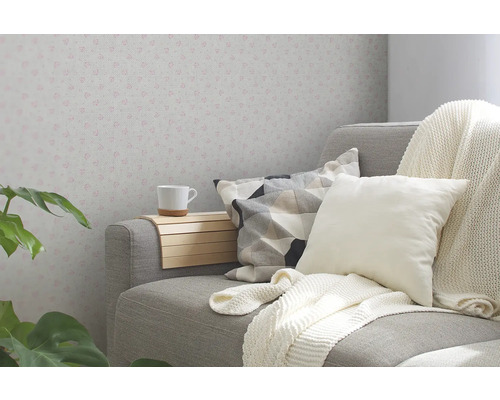 Wohnzimmer mit grauer Couch, Kissen, Decke, Getränkehalter und gemusterter Tapete