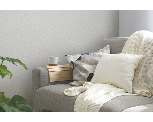 Gemütliche Sitzecke mit Sofa, Kissen, Decke und Armlehnentablett für eine Tasse