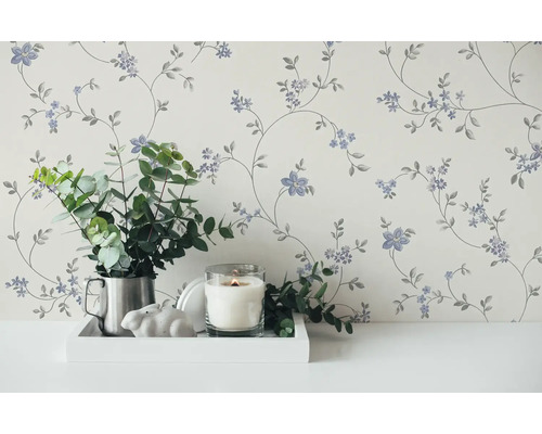 Dekorative Tapete mit Blumenmuster in einem hellen Raum, kombiniert mit einer Kerze und grünen Pflanzen.