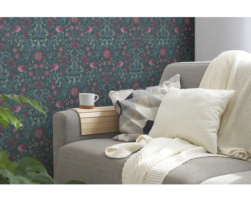 Wohnzimmer mit floraler Tapete, Sofa, Kissen und Decke