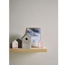 Dekorative Häuser aus Beton und Holz auf einem Regal mit einer Fotografie.