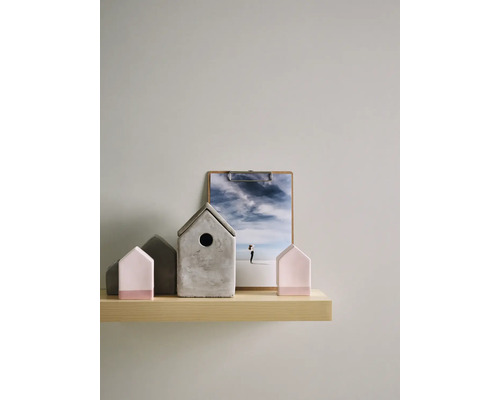 Dekorative Häuser aus Beton und Holz auf einem Regal mit einer Fotografie.