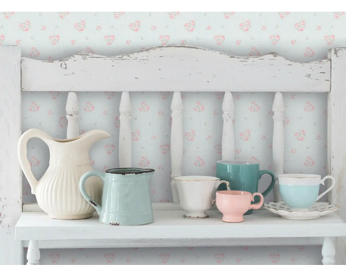 Dekorative Szene mit verschiedenen Krügen und Tassen auf einem weißen Regal vor einer floralen Tapete.