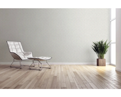 Wohnraum mit gemusterter Tapete, Sessel, Fußhocker, Zimmerpflanze und Holzboden für eine helle und freundliche Atmosphäre.