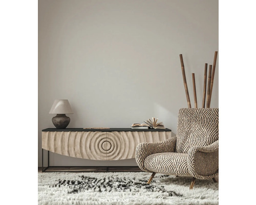 Wohnzimmer-Interieur mit gemustertem Sessel, Sideboard, Lampe und Teppich für eine gemütliche Atmosphäre.