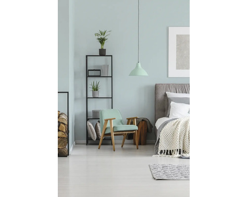 Schlafzimmer mit Bett, Sessel, Regal und Lampe