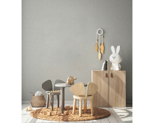 Helles Kinderzimmer mit Kindermöbeln, Spielzeug und einer dezent gemusterten Tapete.