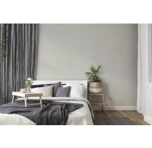 Hell eingerichtetes Schlafzimmer mit Bett, Nachttisch, Vorhängen und Dekorationen