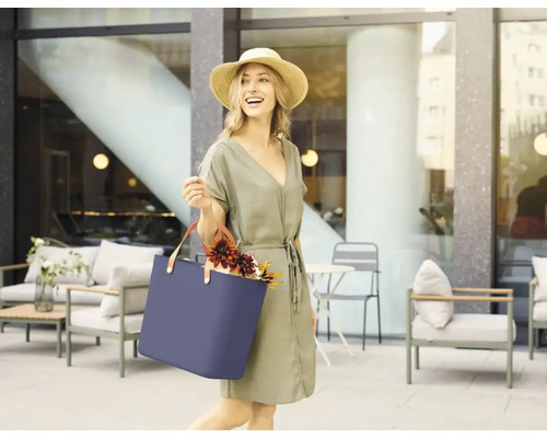 Frau mit Strohhut und blauer Tragetasche im Außenbereich