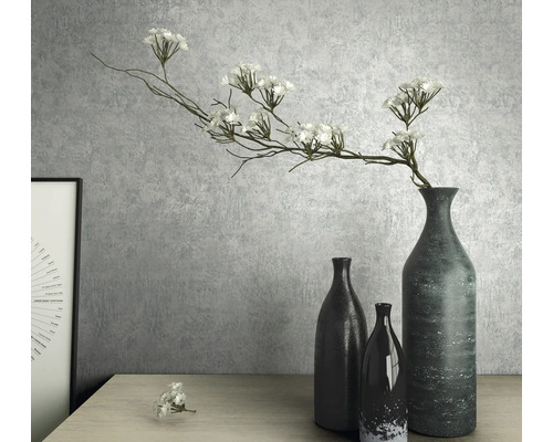 Dekoratives Stillleben mit Vasen und Kunstblumen auf einem Tisch.