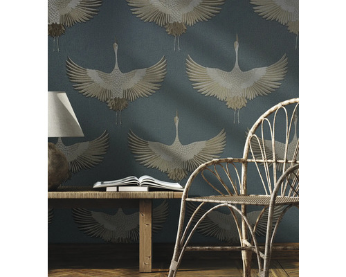 Szene mit einem Rattansessel, einem Holztisch mit Buch und einer Tapete mit Kranichmuster.