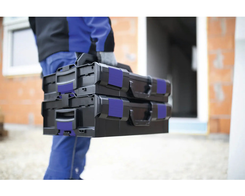 Handwerker trägt zwei schwarze Werkzeugkoffer zum Einsatzort