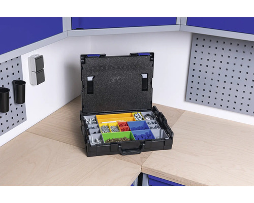 Offener Sortimentskasten mit diversen Schrauben und Kleinteilen auf einer Werkbank