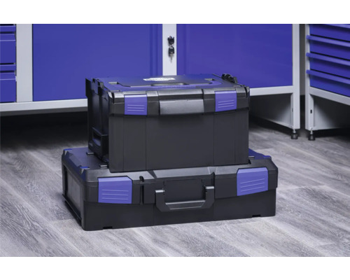 Zwei schwarze Werkzeugkoffer mit blauen Verschlüssen gestapelt vor einem blauen Werkstattschrank.