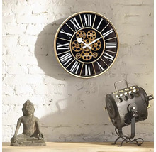 Dekorative Wanduhr mit römischen Ziffern und sichtbarem Uhrwerk neben einer Buddha-Statue und einer Lampe