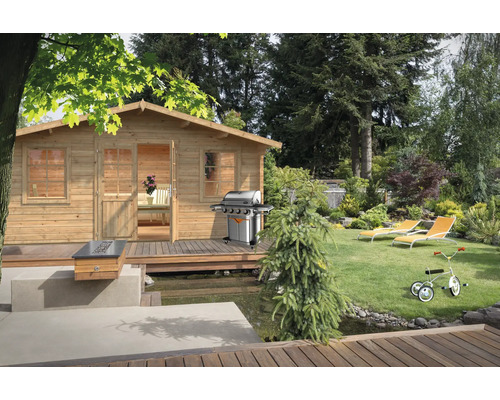Gartenhaus Palmako Klara 17,0 m² 518 x 420 cm Tauchgrundiert braun Szene mit einem Holzgartenhaus, Grill, Liegestühlen und einem Kinderdreirad in einem Garten.