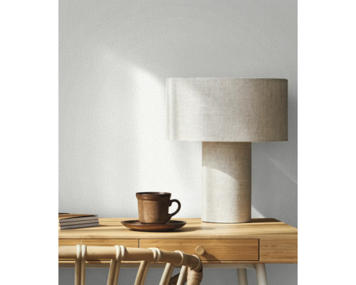 Dekoratives Zimmer mit Tischleuchte, Tasse, Notizbüchern und Rattanstuhl