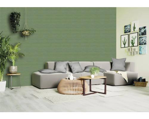 Wohnzimmer mit Couch, Tisch und Zimmerpflanzen vor einer strukturierten Tapete