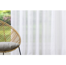 Heller Raum mit weißem Vorhang und Sessel aus Rattan