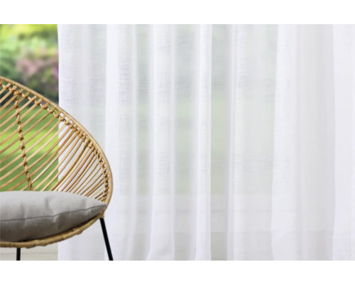 Heller Raum mit weißem Vorhang und Sessel aus Rattan