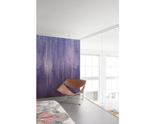 Schlafzimmer mit lila Blumenmustertapete und Ledersessel