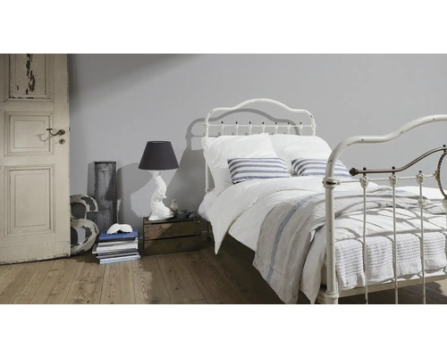 Schlafzimmer mit Metallbett, Nachttischlampe und Holzboden