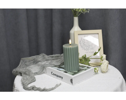 Dekoratives Arrangement mit geriffelter Kerze, Buch und Blumenvase