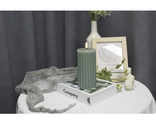 Dekorative grüne LED-Kerze auf einem Buch auf einem Tisch