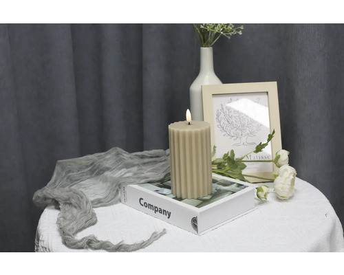 Dekorative gerippte Kerze auf einem Tisch mit Buch und Dekorationen