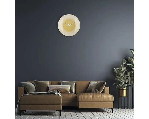 Wohnzimmer mit Sofa, Zimmerpflanze und runder Wanduhr