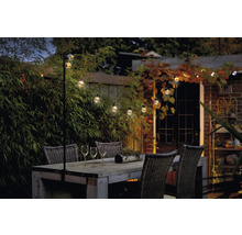 Gartenszene mit Holztisch, Stühlen und Lichterkette für stimmungsvolle Beleuchtung