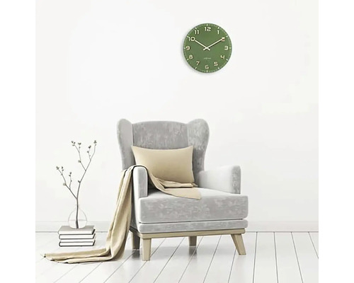 Wohnzimmer mit grünem Wanduhr, Sessel, Kissen und Decke.
