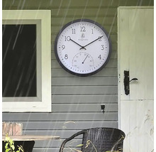 Außenaufnahme einer Wanduhr mit Thermometer an einer Hauswand
