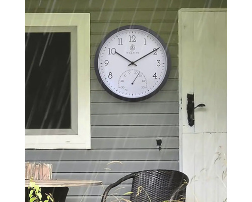Außenaufnahme einer Wanduhr mit Thermometer an einer Hauswand
