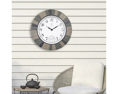 Außenuhr mit Thermometer an einer Wand über einem Stuhl und einem Tisch.