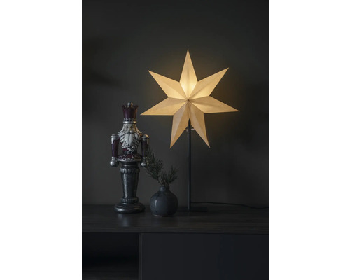 Dekoratives Arrangement mit Nussknackerfigur, Tannenzweigvase und Papiersternleuchte auf einem Schrank