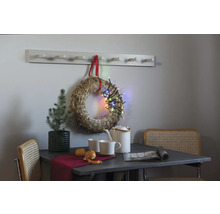 Dekoratives Stillleben mit Tisch, Stühlen, Kranz, Lichterkette und Garderobe