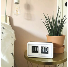Szene mit einem Nextime Retro Flip-Uhr auf einem Tisch neben einem Bett und einer Zimmerpflanze